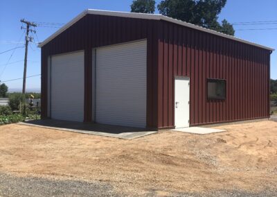 Red metal shop building with white roll up doors butte county